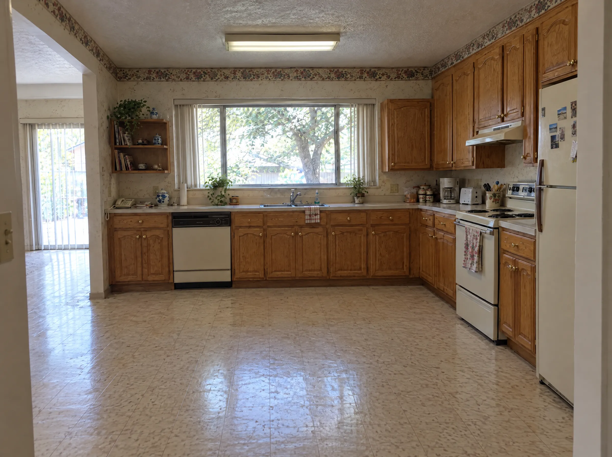 Before: the same kitchen from the dining doorway, wallpaper border and almond appliances