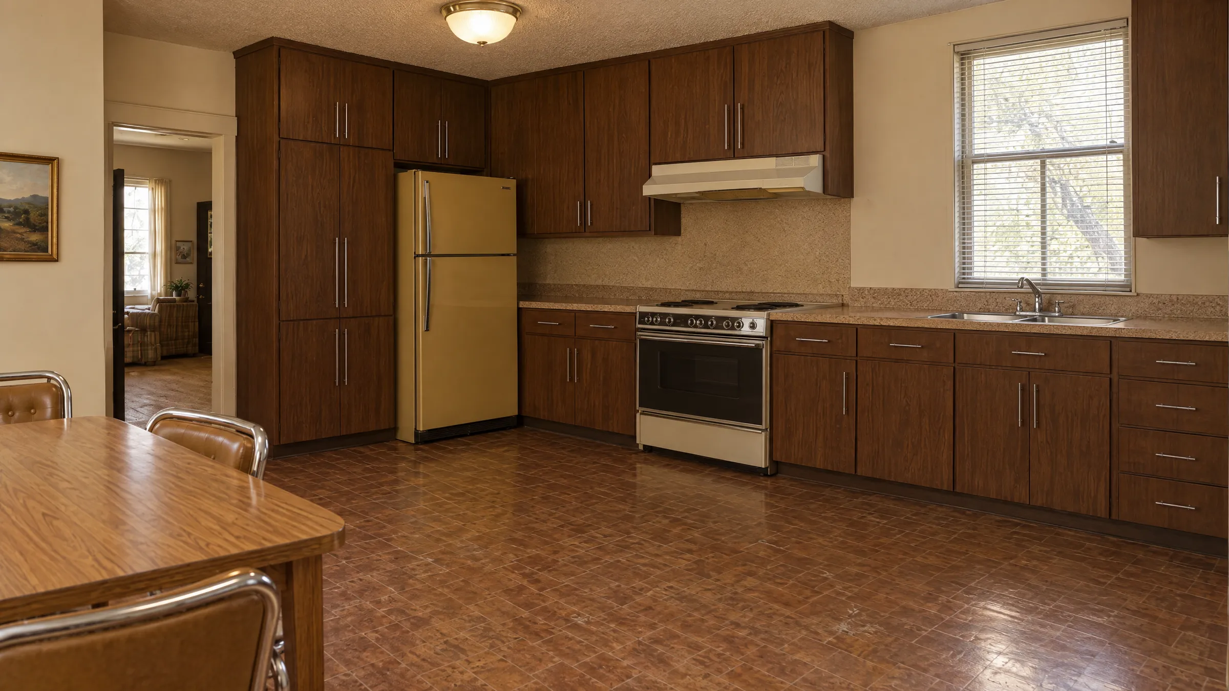 The same kitchen before remodeling, with dark flat-front cabinets, laminate counters, a harvest-gold refrigerator, and sheet vinyl floors