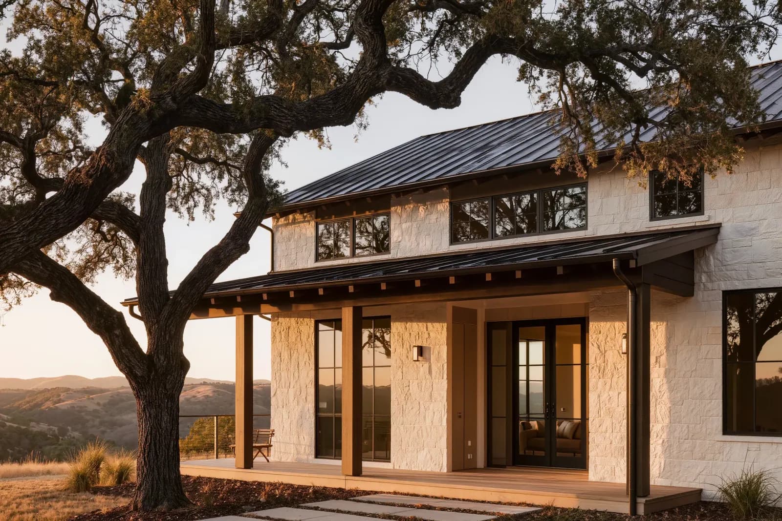 Modern custom home with white limestone walls and dark standing-seam metal roof in the Austin hill country