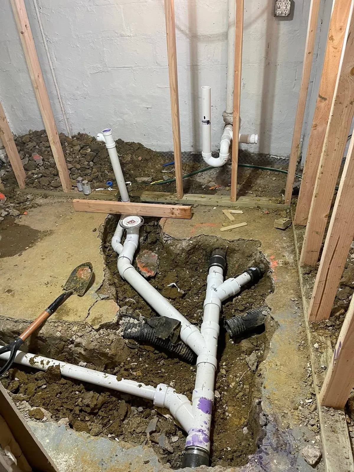 The slab cut open and new PVC drain lines run in the trench