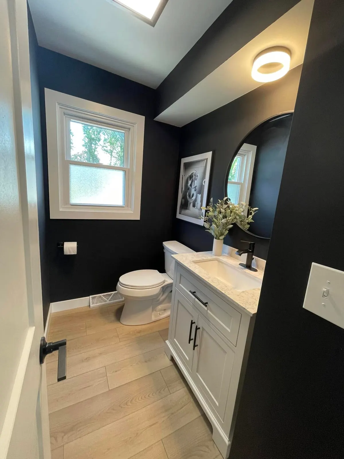 The same powder bath from the doorway, showing the toilet, vanity, and framed artwork