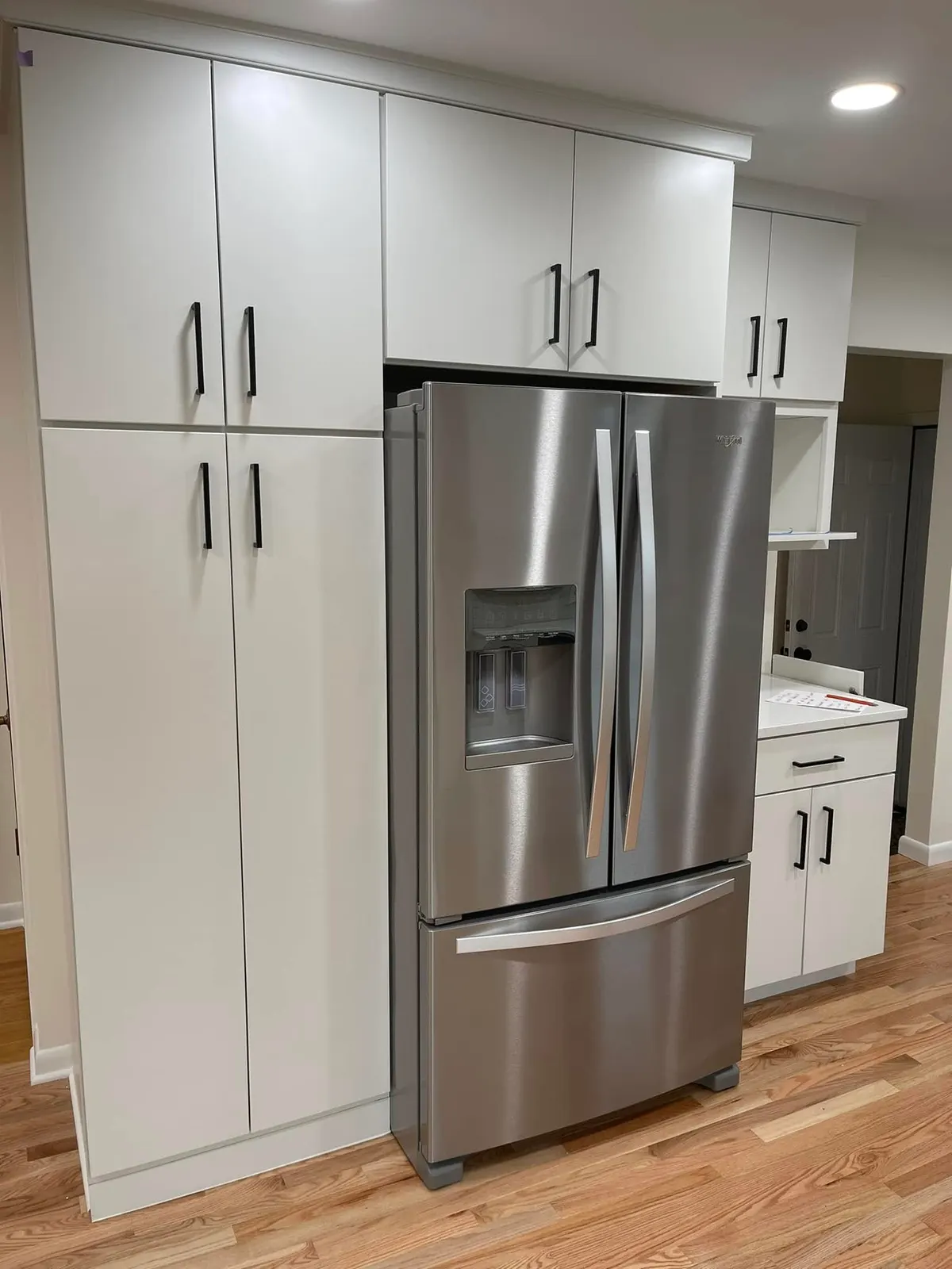 The refrigerator wall with tall white pantry cabinets and stainless French-door refrigerator