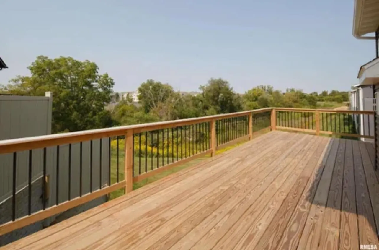 A cedar-tone deck with a black metal rail looking out over trees