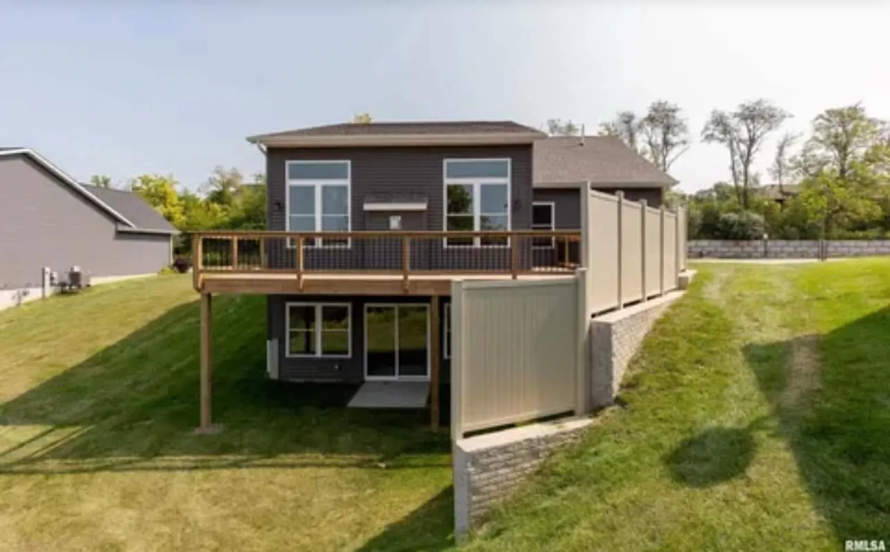 A two-story home with a new upper deck and white privacy fence below