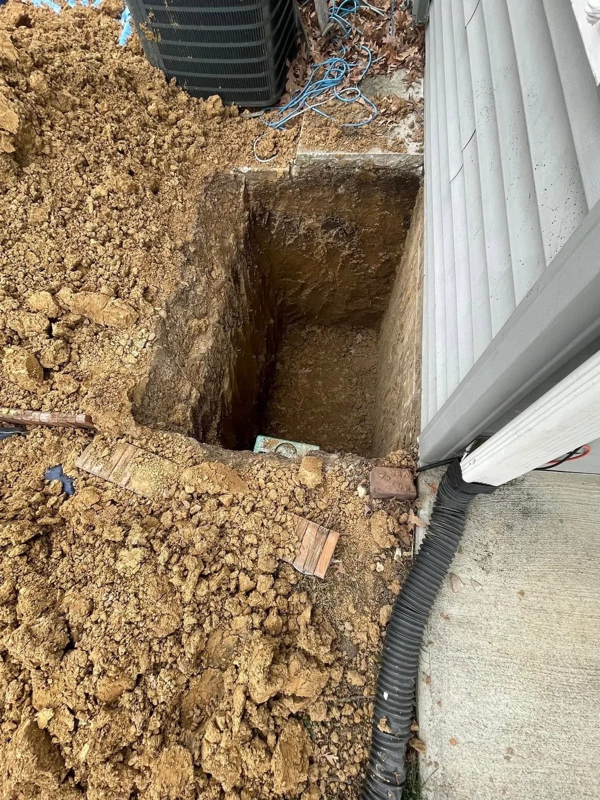 The excavation for an egress window cut beside the foundation