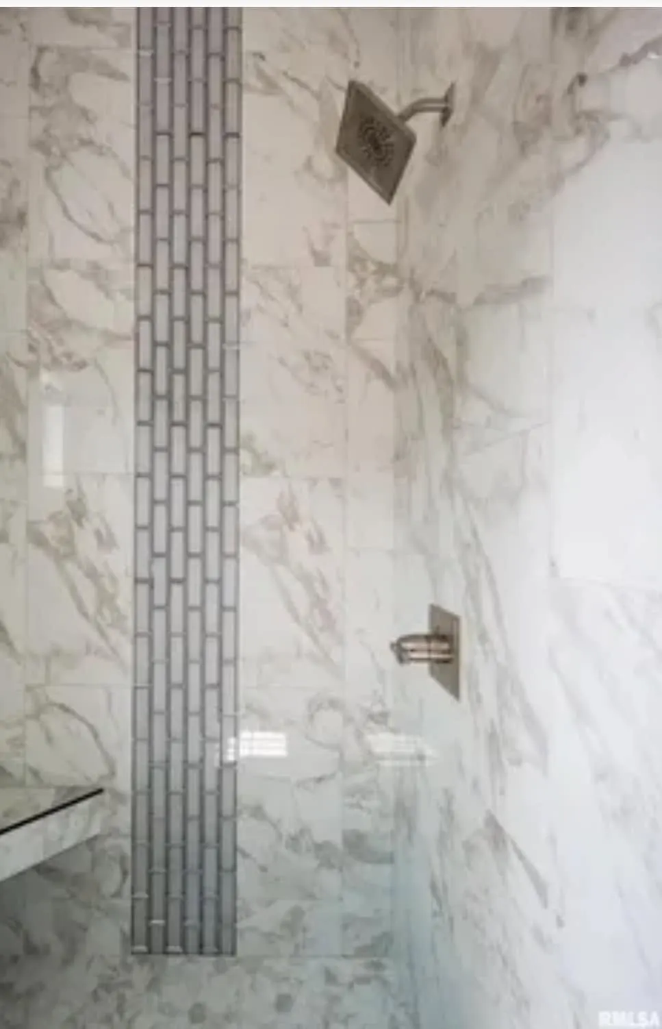 Detail of the shower tile and black hinge hardware on the glass door
