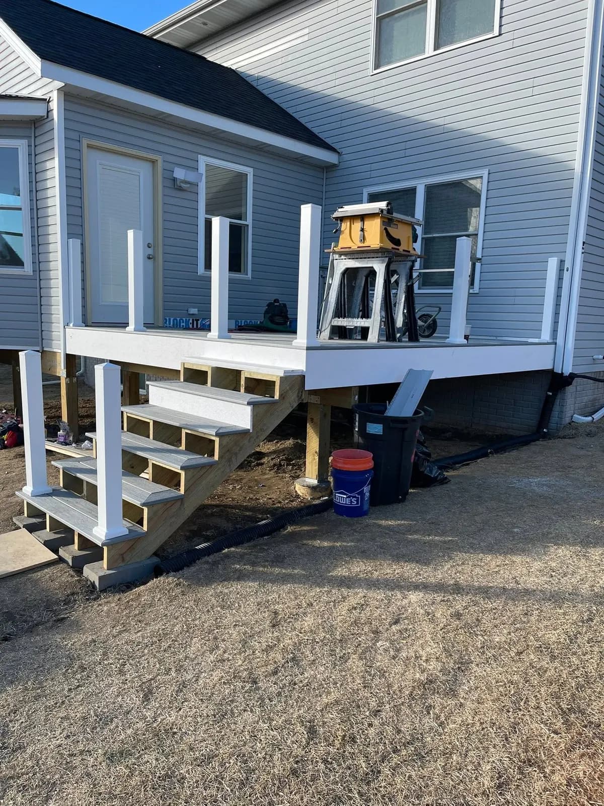 The deck stair framed with white posts set, tools on the platform