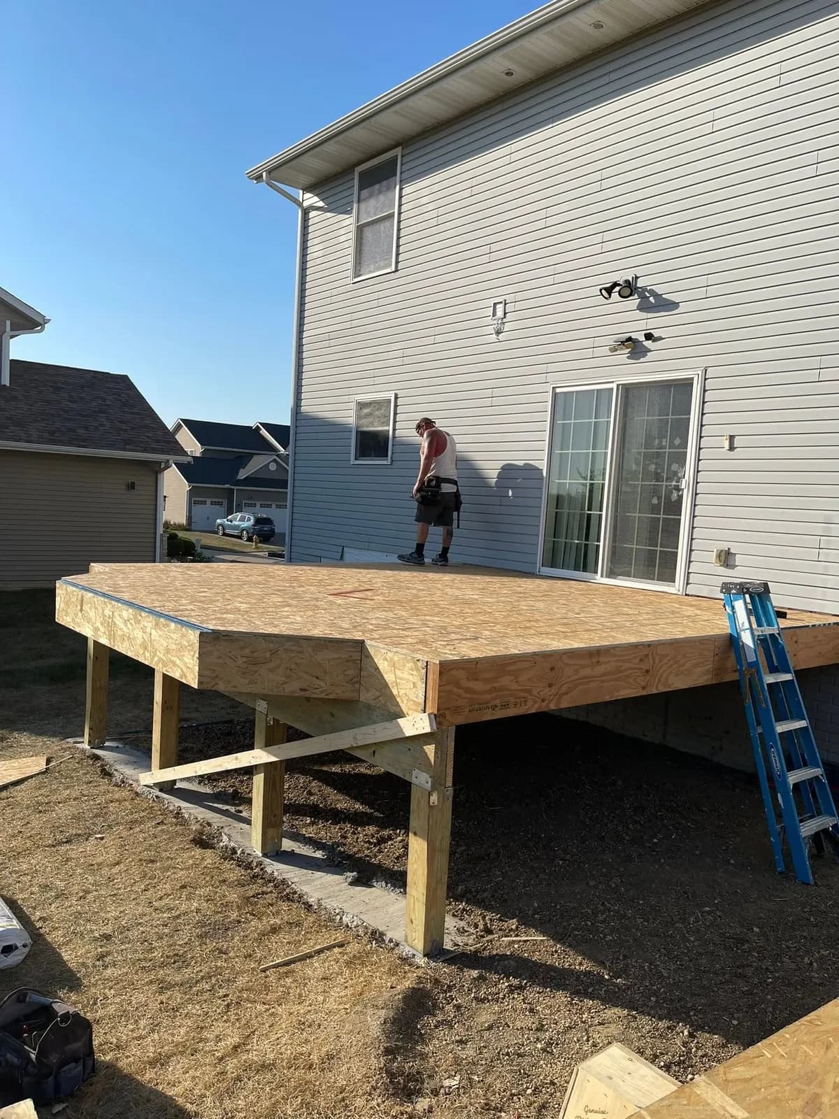 The deck platform framed and decked, with the builder working on the far edge