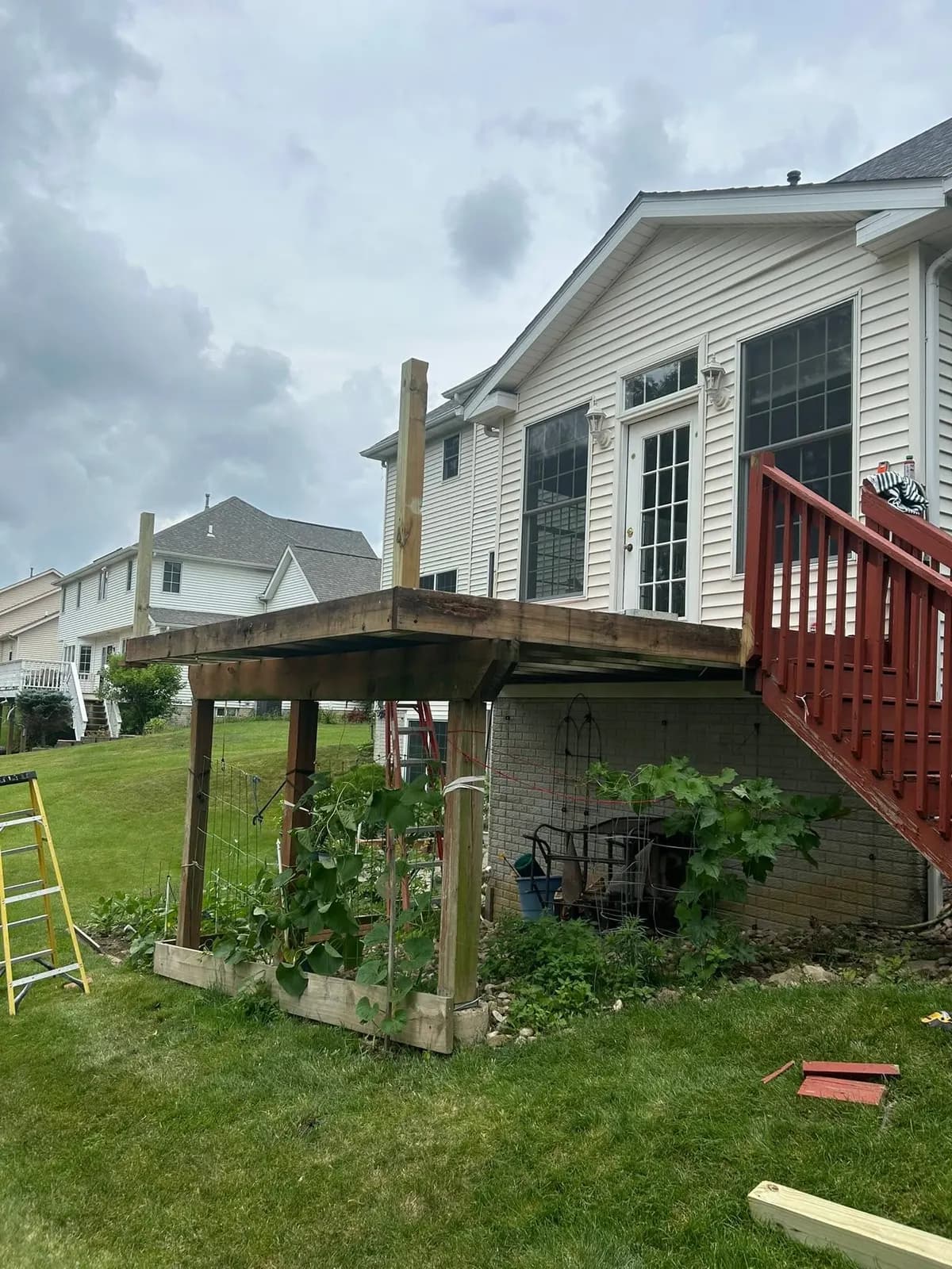 Before: the old second-story deck with weathered framing and a red-stained stair rail