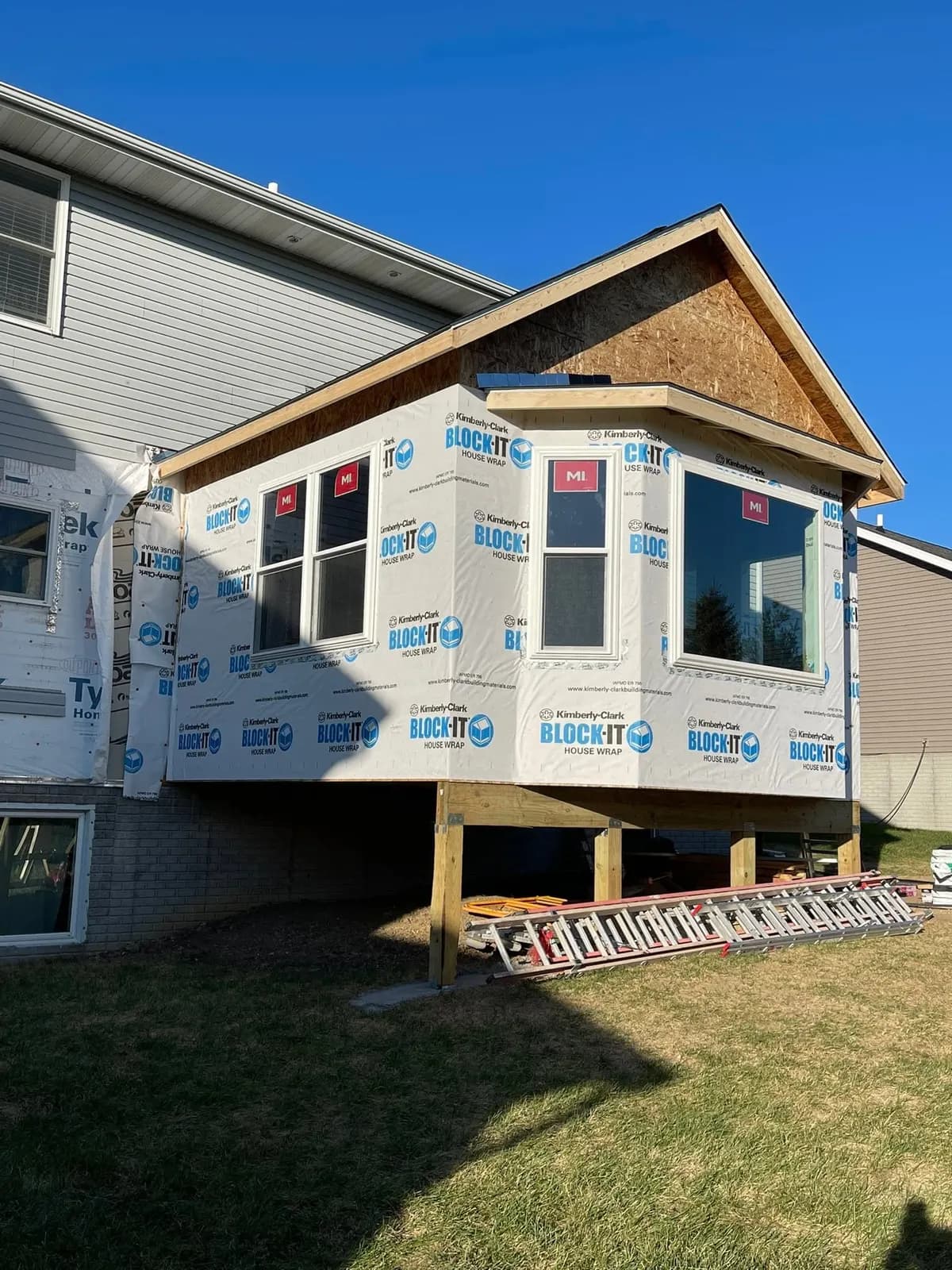 The addition wrapped and windows installed, with the deck below framed