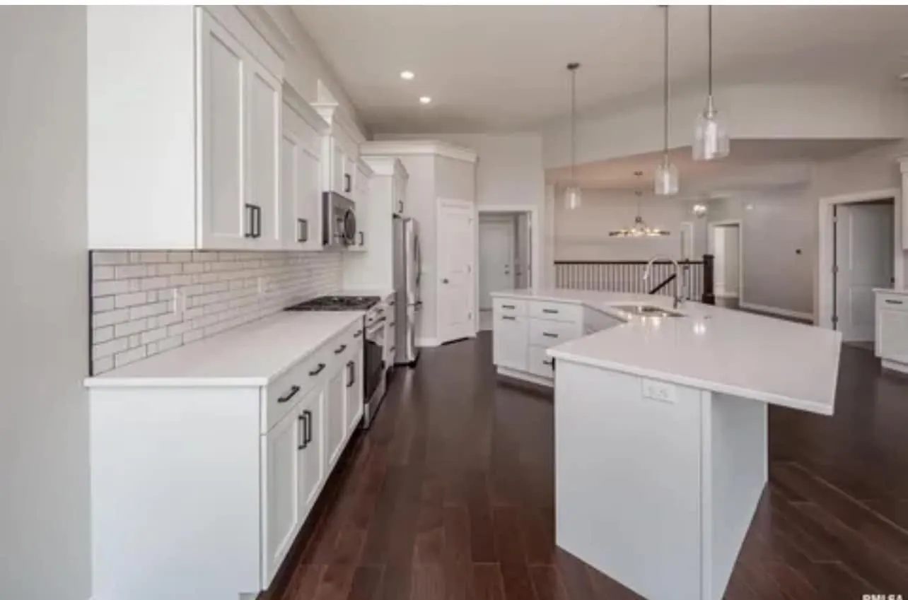 The white kitchen with quartz counters and pendant lights over the island
