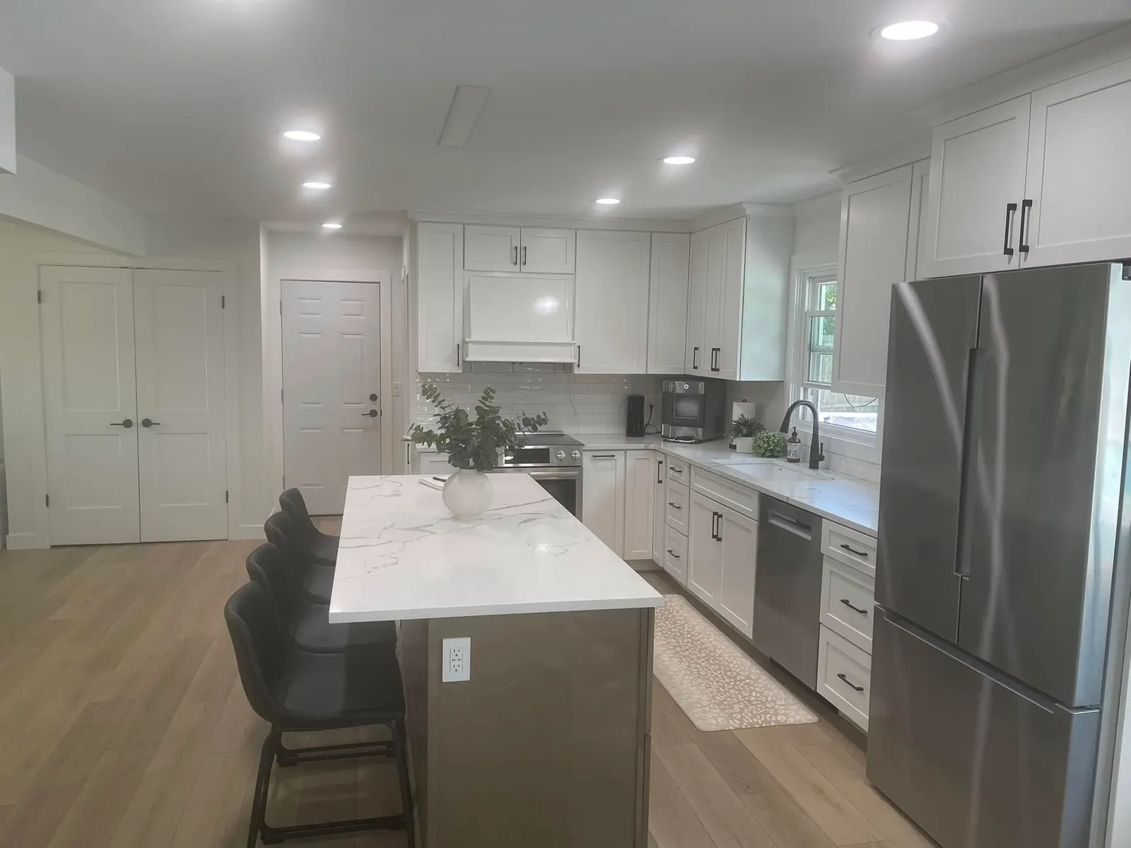 The kitchen island with stools, stainless appliances, and pendants